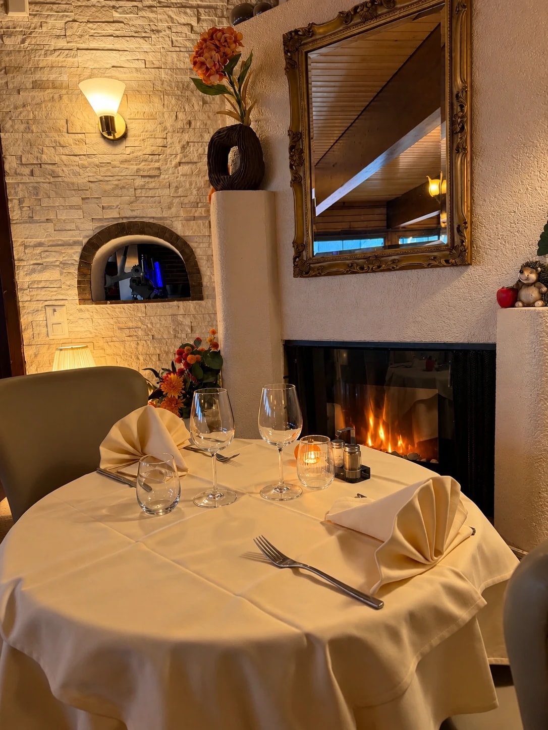 Table dressée pour deux près de la cheminée, bougie et verres à vin